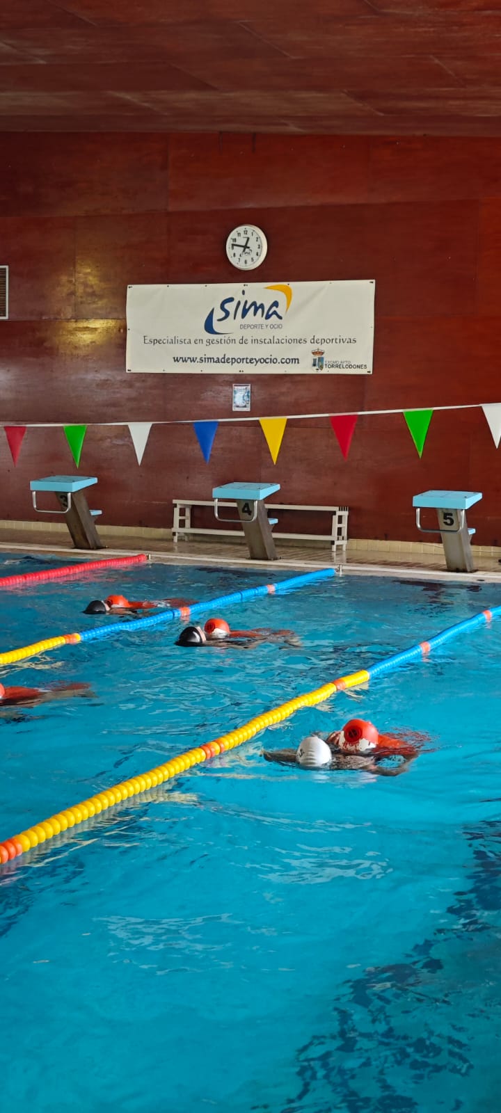 Alumnos practicando rescate acuático con maniquíes en el curso de socorrista de SIMA en una piscina cubierta